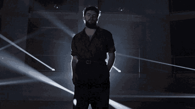 a man with a beard is standing in the dark