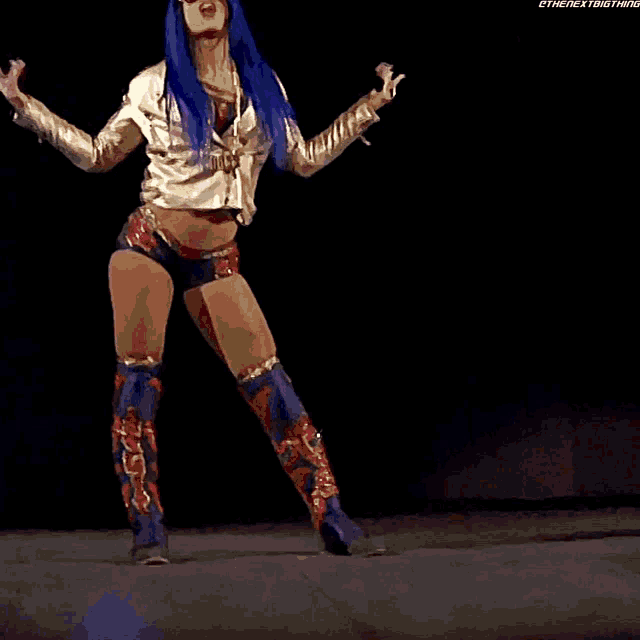 a female wrestler is standing on a stage with a blue light behind her and the words " the next thing " on the bottom
