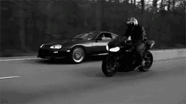 a man is riding a motorcycle next to a car on the road .