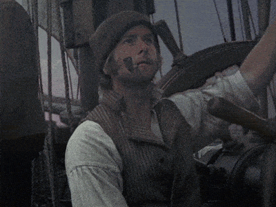 a man wearing a striped vest and a hat is smoking a cigarette on a boat
