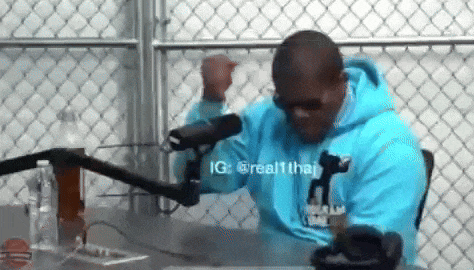 a man wearing a blue hoodie is sitting in front of a microphone .