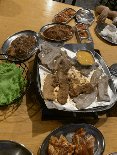 a table topped with plates of food including meat and sauces