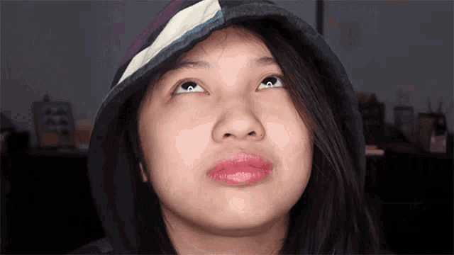 a young woman wearing a hooded jacket looks up at the sky