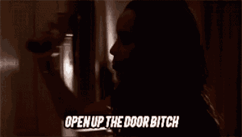 a woman is standing in a dark hallway with the words `` open up the door bitch '' above her .