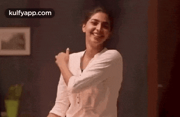 a woman in a white shirt is dancing in a room .