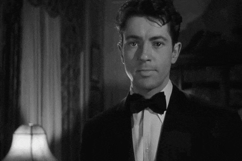 a man wearing a tuxedo and bow tie looks at the camera