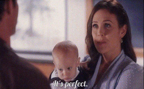 a woman is holding a baby in her arms and a man is standing behind her .