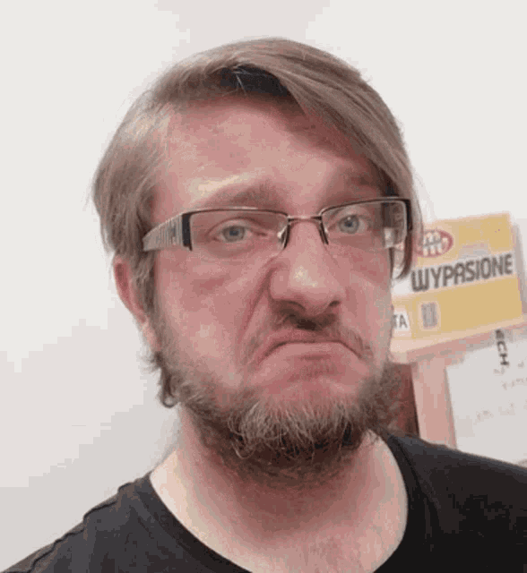 a man wearing glasses and a black shirt is making a funny face in front of a box that says wypasione