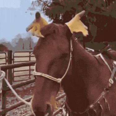 a brown horse wearing a yellow ear covering