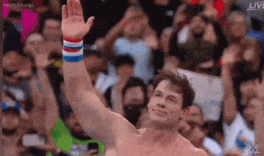 a wrestler is waving his hand in front of a crowd .