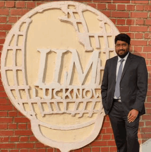 a man in a suit and tie is standing in front of a brick wall with a large sign .