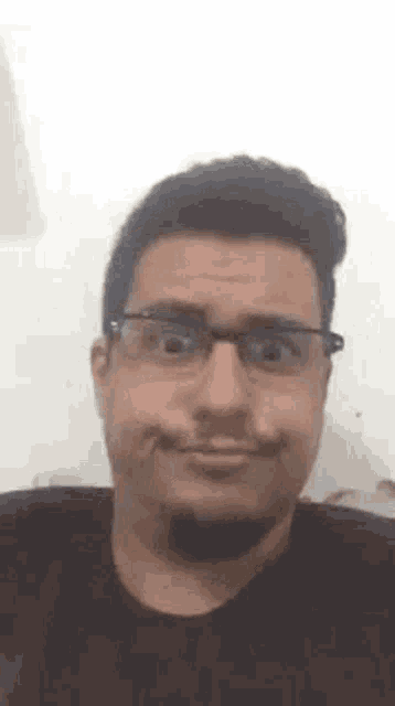 a man wearing glasses is making a funny face while looking at the camera .