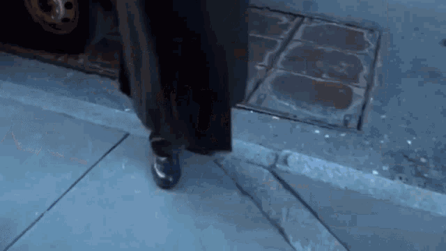 a man in a black coat is walking down a sidewalk