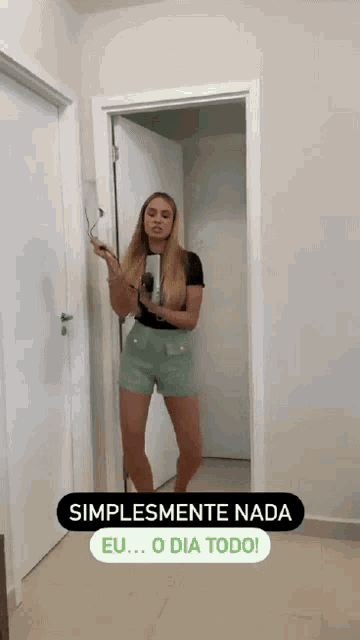 a woman standing in a doorway holding a hair dryer and a sign that says " simplemente nada "