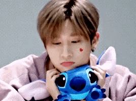 a young man is holding a stuffed animal with a red heart on his cheek