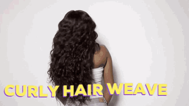 a woman with long curly hair is standing in front of a white wall with the words `` curly hair weave '' written on it .