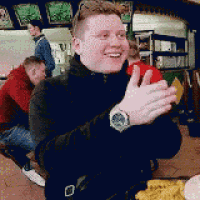 a man wearing a watch is sitting at a table in a restaurant .