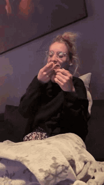 a woman is sitting on a couch eating a hamburger