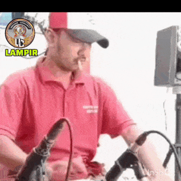 a man in a red shirt and hat is smoking a cigarette while playing a dj set .