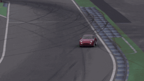 a red car is driving down a road with white stripes