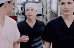 a group of nurses are standing next to each other in a hospital hallway talking to each other .