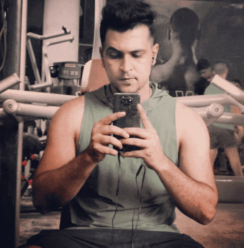 a man is taking a picture of himself in a gym while wearing a green tank top