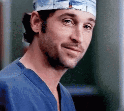 a close up of a man wearing a scrub hat and a blue shirt .