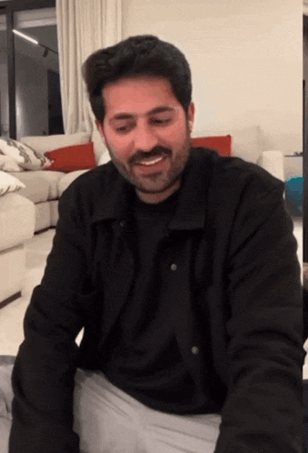 a man with a beard wearing a black shirt is smiling