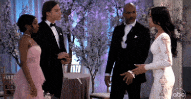 a man in a tuxedo and a woman in a white dress are standing next to each other