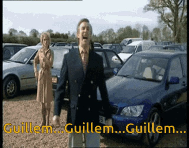 a man in a suit and tie stands in front of a blue car with the words guillem guillem guillem guillem