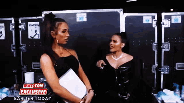 two women talking in front of a sign that says wwe com exclusive