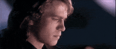 a close up of a man 's face in a dark room with a blue background .