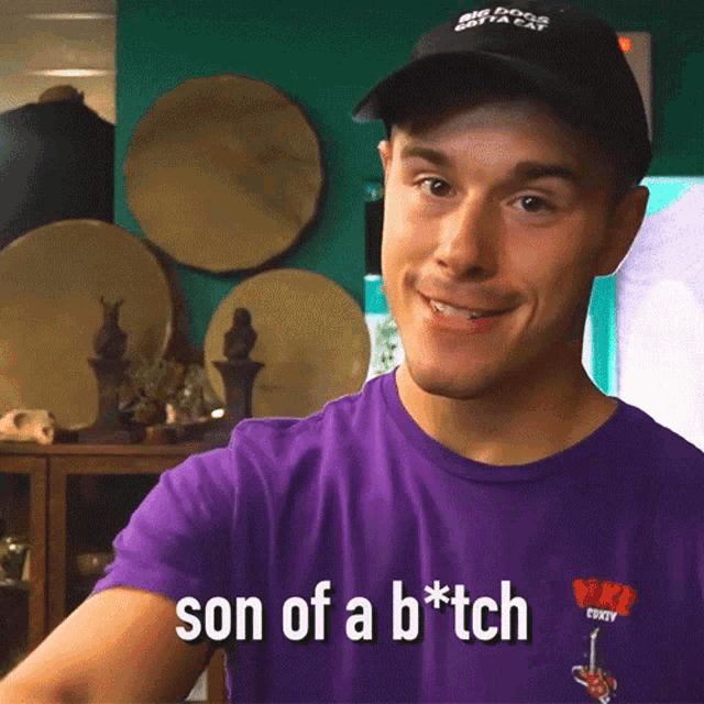 a man wearing a purple shirt that says son of a b * tch on it