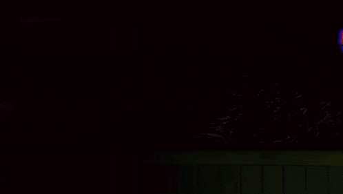 a black cat with yellow eyes is sitting in the dark