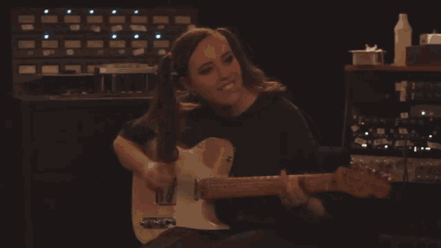 a woman is playing a guitar in a dark room