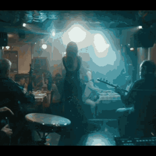 a man playing a guitar in a dark room with a woman singing