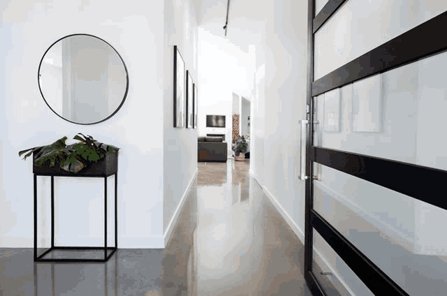 a long hallway with a plant on a table and a mirror