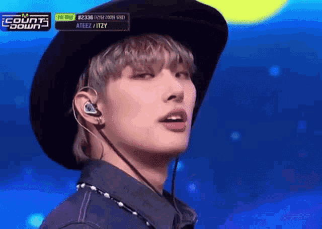a close up of a person wearing a hat and earbuds on a stage .