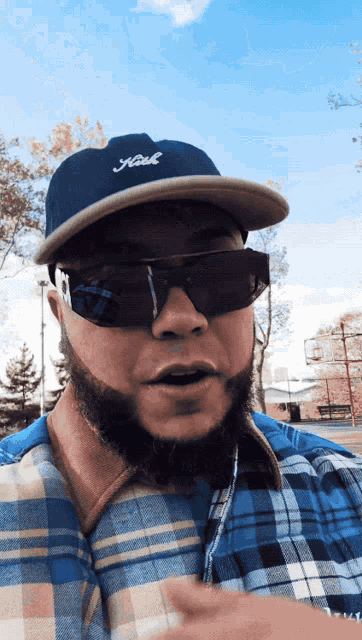 a man with a beard wearing sunglasses and a hat with the word hook written on it