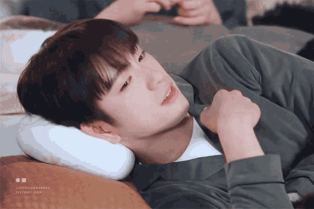 a young man is laying on a couch with a pillow on his head