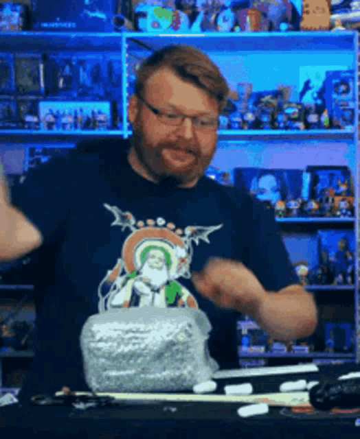 a man with a beard wearing a blue shirt with a picture of santa claus on it