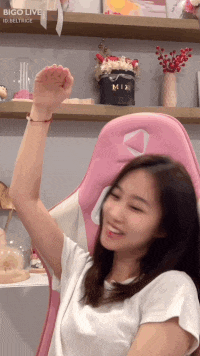 a woman sitting in a pink chair with her arms in the air