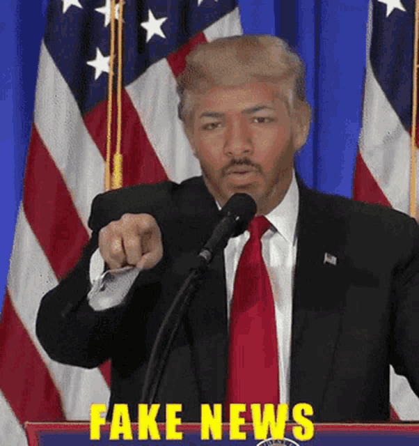 a man in a suit and tie is giving a speech with fake news written on the bottom
