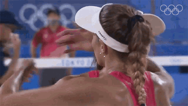 a woman wearing a visor and a braided ponytail is hugging a man .