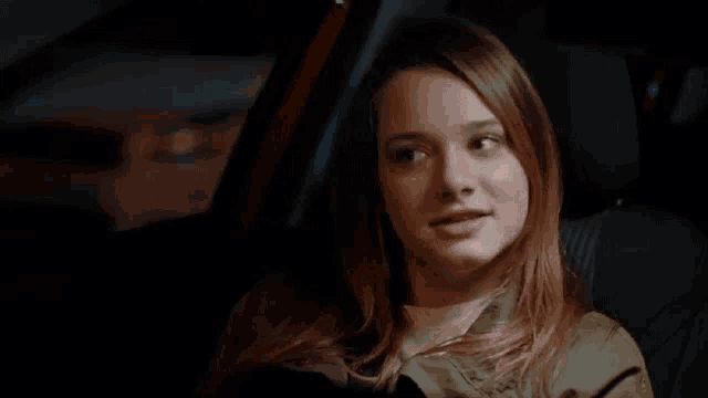 a young woman is sitting in the back seat of a car .