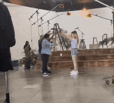 a group of people are standing in a room with a ladder in the middle