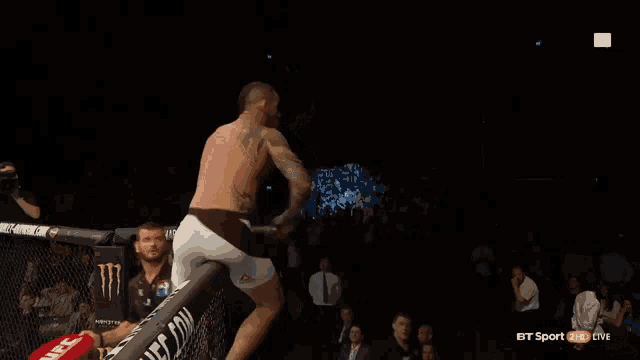 a man with a tattoo on his arm is standing in a boxing ring .