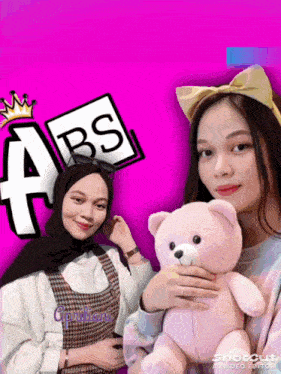 a girl is holding a teddy bear in front of a sign that says abs on it