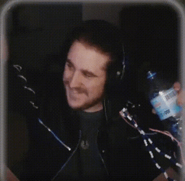 a man wearing headphones is holding a bottle of aquafina