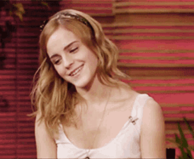 a woman wearing a white tank top and a headband is smiling